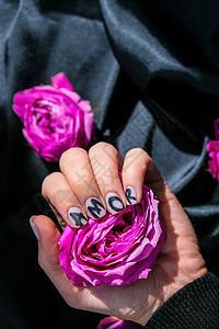 指甲修指甲上的 AMOR 字样在黑色丝绸织物上挂着粉红色的玫瑰花 最小的平躺自然 女手 爱护理艺术沙龙温泉女士指甲油抛光凝胶魅力图片