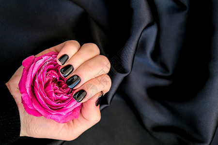 黑钉子修甲把粉红玫瑰花放在黑色丝质织物上 最小的平板性 女性手玫瑰设计美容美甲奢华皮肤温泉丝绸艺术护理图片