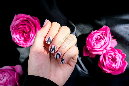 指甲修指甲上的 AMOR 字样在黑色丝绸织物上挂着粉红色的玫瑰花 最小的平躺自然 女手 爱爱情女士手指指甲油魅力温泉化妆品表皮设图片