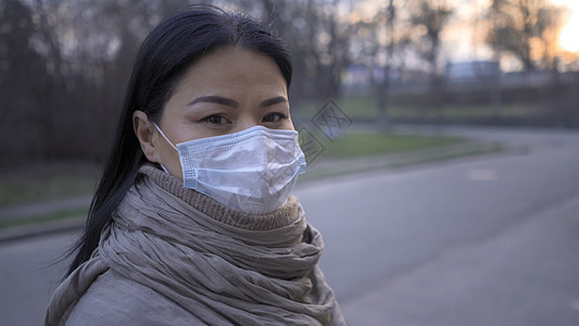 身戴面具的亚洲妇女站在空城街上图片