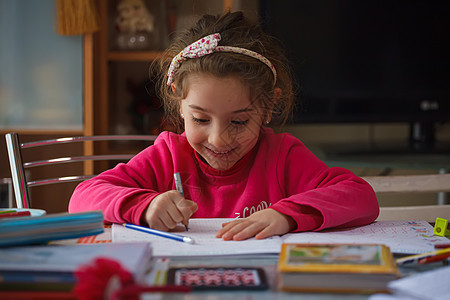 微笑的6岁女孩做功课学习家庭作业教育写作瞳孔案件学校钢笔教学桌面图片