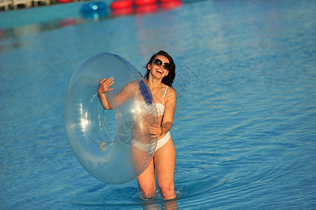 穿着白色泳衣的女人 在水公园里 一个带充气圆环的女人比基尼水池水族魅力旅行假期太阳棕褐色晴天女孩图片
