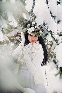 一个穿着白色衣服的女人在寒冷的冬天森林里的画像 在白雪覆盖的冬季森林里 头戴花环的女孩镜头裙子艺术新年女士木头帽子新品花园假期图片