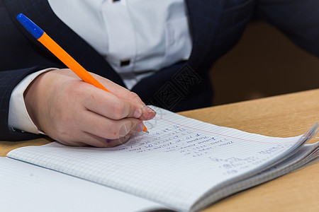 手拿笔记本男孩手拿一支喷泉笔 用蓝墨水能解答数学的例子手指计算数字孩子男生写作教训教育课堂木板背景