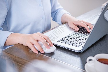 商业概念 穿蓝衬衫的女士在电脑上打字 办公室桌上有咖啡 背光 太阳光亮效应 特写 侧视图 复制空间咖啡店人士手机自由职业者工作女图片