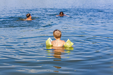 在一个非常炎热的夏日 一家人 一位父亲和他的儿子们正在河里游泳 在水库游泳 一个幸福的家庭在夏天玩得开心 在水中嬉戏孩子童年乐趣图片