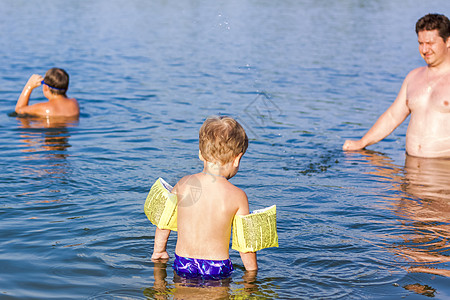 河里游泳孩子在一个非常炎热的夏日 一家人 一位父亲和他的儿子们正在河里游泳 在水库游泳 一个幸福的家庭在夏天玩得开心 在水中嬉戏沙滩孩子们泳背景