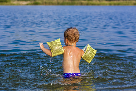 在炎热的夏日 一个快乐的孩子正在河里游泳 在水库游泳 一个幸福的家庭在夏天玩得开心 在水中嬉戏沙滩泳装父亲池塘童年太阳海洋孩子们图片