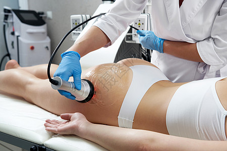 超声空化塑身治疗 在美容院接受抗脂肪团和抗脂肪治疗的妇女病人美容师女性程序保健沙龙组织空化卫生超声波图片