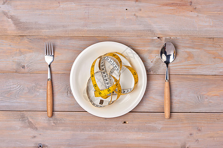 配有测量胶带 刀和叉子的板块 木制桌上的健康食品图片