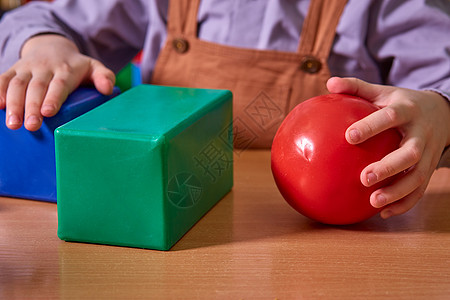 一个红球和一个蓝色立方体 在一个孩子的手里图片