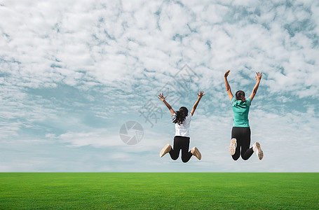 妈妈和女孩在绿地上跳 与蓝天相对立图片