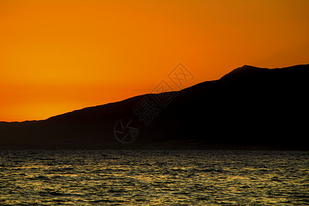 日落时山和橙色天空的海景卡波海洋山脉海滩太阳热带公园海浪地平线橙子图片