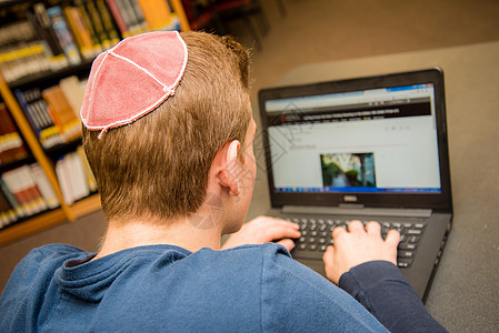 身穿Yarmulke背部的犹太男孩坐在教室里 与学生一起上课成人架子笔记本年轻人学校男人知识男性学习店铺图片