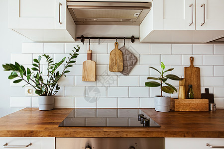 厨房黄铜器具 厨师配件 有白色瓦片墙壁和木桌面的垂悬的厨房 厨房背景的绿色植物瓷砖柜台住宅窗户公寓桌子器具房子建筑学装饰图片