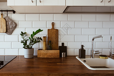 厨房黄铜器具 厨师配件 有白色瓦片墙壁和木桌面的垂悬的厨房 厨房背景的绿色植物内阁窗户滚刀植物木板财产烤箱瓷砖木头橱柜图片