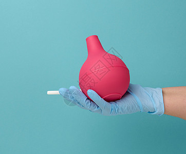 蓝色医用手套上戴着蓝底的粉红色橡胶灌肠医生医院程序卫生空气灯泡疼痛注射工具护士图片