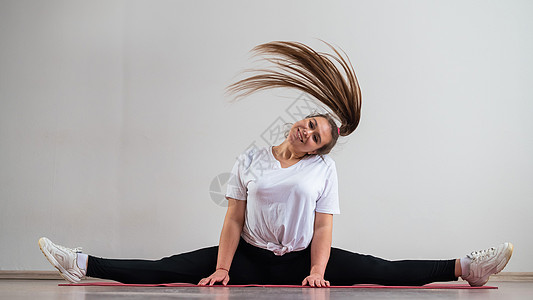 针垫花一个年轻柔软的胖女人 坐在横针纹床上 在白种背景下摇发晃发体操减肥俱乐部运动员卫生缠绕体育锻炼保健训练运动装背景