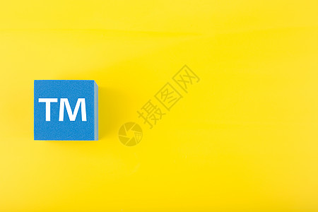 黄色背景蓝色玩具立方体上的 TM 商标标志 带复制空间服务财产专利执照首都金融会计知识分子工作版权图片