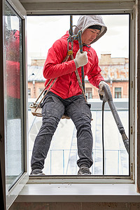 窗户打开时挂着一个攀爬齿轮的窗垫商业办公室工人男人危险职业垫圈工作风险装备图片