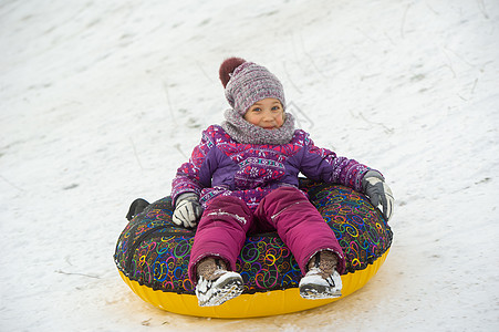 一个冬天的小女孩 穿着紫色衣服和一个充气圆圈 在街上的山下骑马游乐街道设施新年下坡雪花圣诞礼物孩子女孩帽子图片