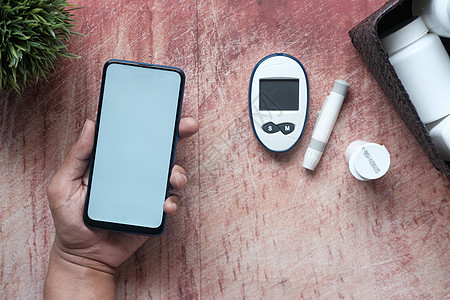 手持智能电话和糖尿病测量工具的桌面上图片