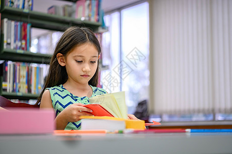 可爱的小女孩在学校图书馆专心看书 女孩在课堂外专注于自学 教育和人们的生活方式 学术和儿童职责概念图片