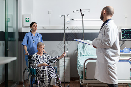 生病的老年老妇坐在轮椅上 手臂上有IV滴滴袋临床男人输液病房医师诊所保健医生治疗静脉图片