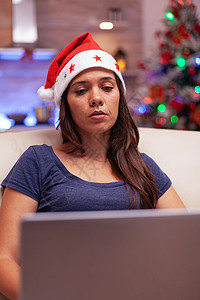 圣诞节老人圣诞节期间工作时用笔记本电脑使用的女孩阅读业务电子邮件女士沙发乐趣消息娱乐闲暇互联网技术房间长椅背景