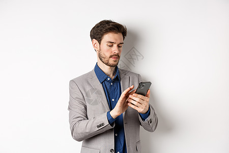 商务男人素材穿着西装的年轻商务人士在手机上发短信 看着智能手机 站在白色背景下推销员工作电话男人生活广告男性工作室成功商务背景