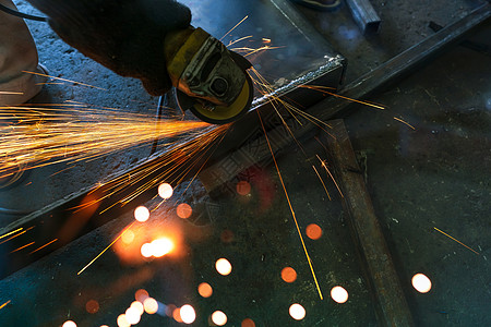 使用角磨机在焊缝上磨削金属的产业工人 工人使用角磨机并产生火花 用于切割钢材的工具 工业工作场所的安全 金属工厂行业图片