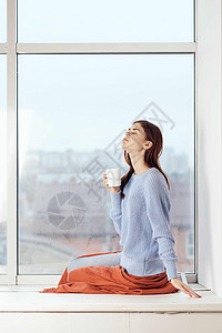 女人靠近窗边的梦幻女郎 在家里安心休息吧女孩女士杯子格子思维咖啡女性假期闲暇背景图片