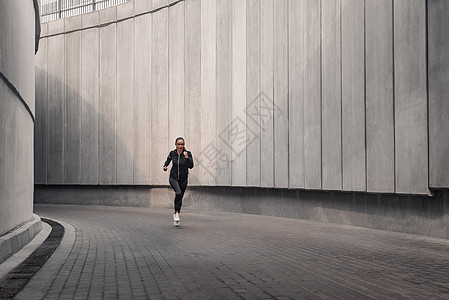 青年运动员正在体育场附近跑步训练慢跑者石头女性阳光海岸女士有氧运动活力阴影图片