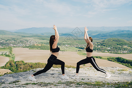 两个女孩在悬崖上玩运动 天性瑜伽青菜腰部蓝色蒸汽树木空气石头训练女孩山脉图片
