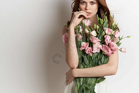 美丽的女人手握着鲜花 装饰有魅力的光彩背景花束头发女孩成人嘴唇花朵粉色女性化妆品白色图片