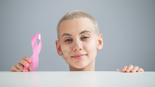 短发的年轻女子身着白色T恤 带着粉色丝带 作为白种背景乳腺癌的象征物全世界女性女孩疾病世界幸存者机构保健考试肿瘤学图片
