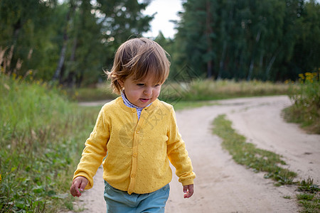 一个蹒跚学步的孩子独自走在荒凉的乡间小路上 牧场或森林农场的乡村沙路图片