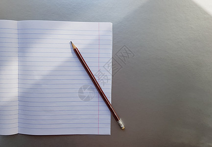 在灰色的桌子上用钢笔打开学校笔记本 阳光从窗户射进来 一张空白的白色笔记本 用于书写 教育理念 复制空间 从上面看 平躺商业床单图片