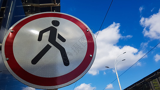 一个白色和红色的圆形路标 中间是一个黑人 在蓝天白云的映衬下禁止行人通行 这个地方不允许行人图片