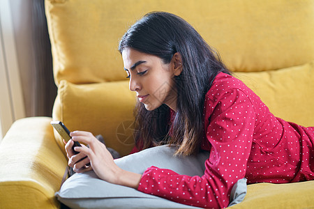 在家使用智能电话的波斯妇女电脑睡衣快乐技术长椅发型房子公寓沙发房间图片