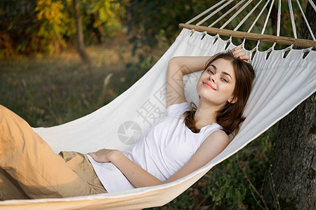 快乐的女人躺在吊床里 自然的清新空气中后院地平线花园女士女孩蓝色享受女性青少年旅行图片