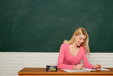 女孩可爱的老师坐在教室黑板背景复制空间 学校教育 正规教育 女学生以创造性和新鲜的想法学习 大学教育 教育理念图片