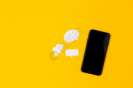 黄色背景上带有纸泡泡的智能手机 沟通理念 顶视图 复制空间 论文作文信使消息短信展示桌子标签讲话技术讨论互联网图片
