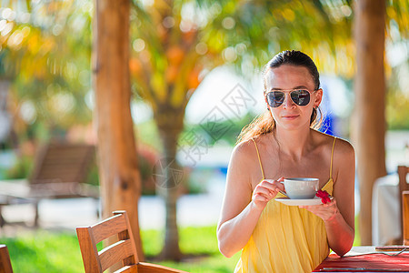 妇女在豪华酒店露台喝热咖啡 在度假餐厅海边观光奢华女性食物阳台成人桌子饮食咖啡店假期景观图片