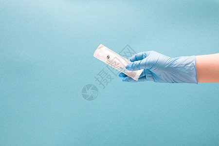 蓝色一次性医用手套中的女手在包裹中握着一次性注射器 蓝色背景复制空间图片