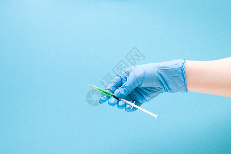U型针蓝色橡胶医用手套中的女手在蓝色背景复制空间 治疗和保健概念 糖尿病概念上握住胰岛素注射器药剂注射疼痛乳胶实验室剂量护士诊所女性免背景