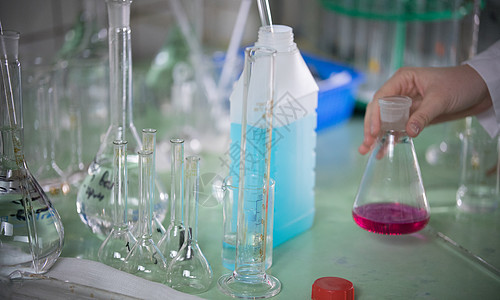 化学实验室 手碰酒瓶的手 表中充满了化学品和烧瓶图片