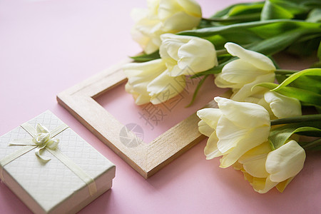 黄色郁金香花 照片框和礼品盒以粉红色背景排列 从上到下 光滑的景色;春天的概念;妇女节图片