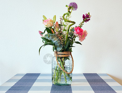 在靠近白墙的现代住宅中 玻璃花瓶中盛放着美丽 鲜艳 色彩缤纷的春花 桌上摆着粉红色和紫色的鲜艳花束 复古夏季装饰图片