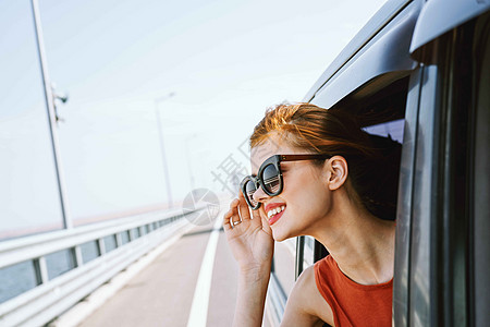 身戴墨镜的妇女在汽车窗外看望着的车窗 旅行生活方式假期驾驶车辆女孩潮人游客晴天冒险司机窗户图片